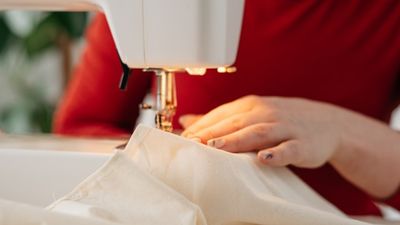 Cream cotton fabric being fed through a sewing machine.