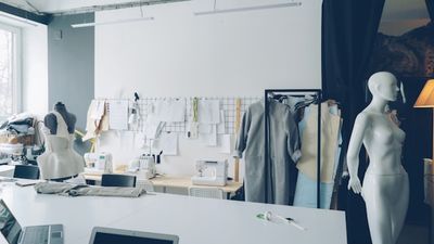 A sewing studio with mannequins, patterns pinned to the wall, and sewing machines.