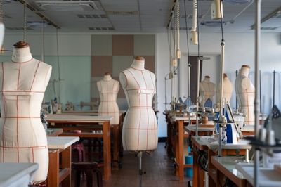Structured dress form mannequins marked with grid lines in a tailoring workshop.