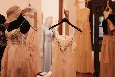 Beaded, flowing dresses displayed on hangers and a dress form in a boutique.