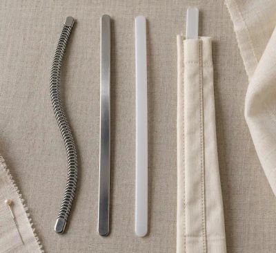 Spiral steel, rigid steel, and plastic boning laid out beside a fabric casing with a strip inserted.