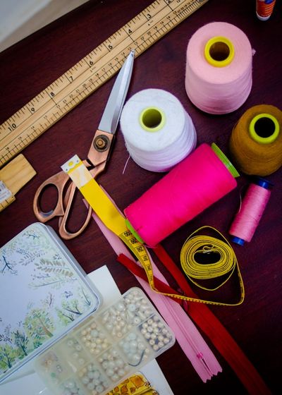 Sewing shears laid out with a ruler, tape measure, zipper, and thread spools.