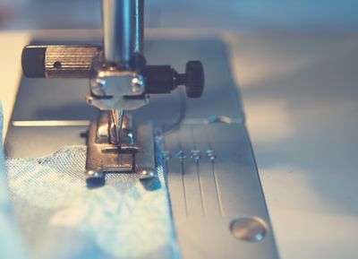 A close-up of a sewing machine stitching blue floral fabric.