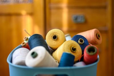 A basket of colorful thread spools against a wooden background.